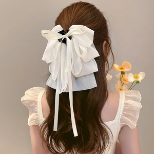 Detail of white tulle bow hair clip with pearl tassels on a model for a sweet style