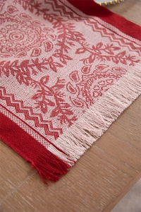 Detailed view of red and beige paisley jacquard table runner with handmade tassels