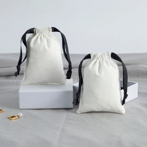 Detailed view of white cotton drawstring jewelry pouches on a minimalist gift box