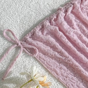 Details von rosa strukturiertem Bikini-Stoff mit Kordelzug und dekorativen Gänseblümchen