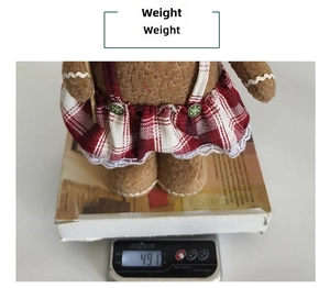 Detail view of gingerbread man plush doll in red plaid skirt on a digital scale weighing 491g