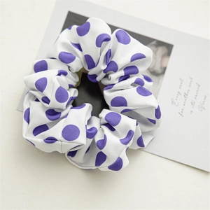 Close-up of white fabric scrunchie with purple polka dots on a decorative card