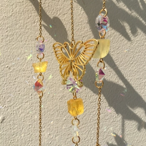 Detail of crystal suncatcher with golden butterfly and yellow stones reflecting rainbow light