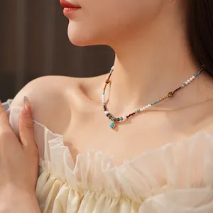 Vintage pearl necklace with turquoise pendant and golden metal beads on a female model