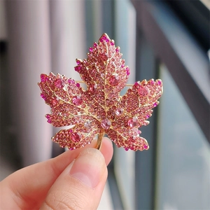 Macro shot of maple leaf brooch with pink crystals and gold-plated alloy detail