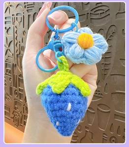 Hand-crocheted strawberry keychain detail with blue yarn stitches and plastic clip