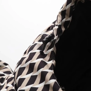 Close-up of geometric pattern fabric and black drawstring toggle on the ski jacket