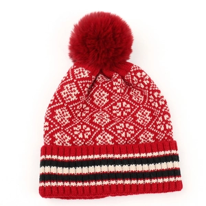Close-up of red knit hat featuring snowflake patterns and a striped ribbed cuff