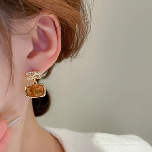 Macro shot of vintage rectangular resin earrings with gold plating on female model