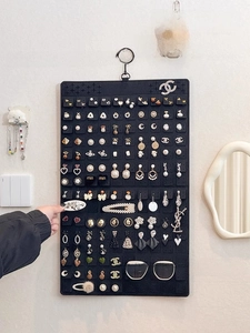 Detailed view of black felt wall hanging organizer with rows of slots for jewelry storage