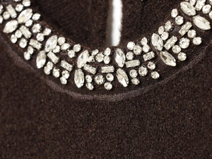 Macro shot of dark brown knitwear with sparkling rhinestone embellishments on the neckline