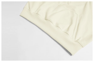Detailed macro view of the cream-colored ribbed hem and kangaroo pocket of the hoodie