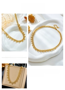 Detailed close-up of a gold titanium chunky chain necklace with spherical bead pendant