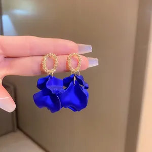 Klein blue petal earrings with golden hollow rings shown in a handheld display