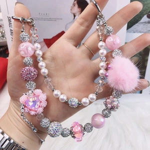 Detail of beaded phone strap with pink heart charm, faux pearls and soft pompom