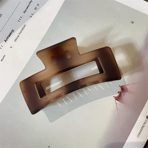 Detailed view of large tortoiseshell matte hair claw clip on lifestyle magazine background