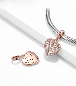 Macro shot of 925 sterling silver heart wing charm with rose gold plating and white zircons