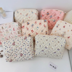 Vue à plat de trousses à maquillage matelassées fleuries avec motifs d'oursons