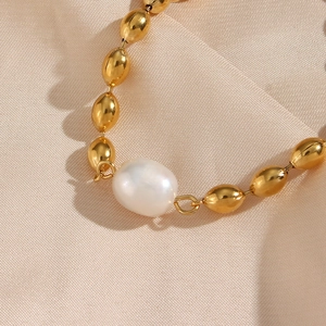 Gold oval steel bead and white baroque pearl necklace set on champagne satin