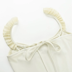 Detailed close-up of cream ruffles and tie-back bow design on a slim fit tank top