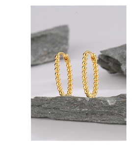 Detailed view of 14K gold-plated beaded hoop earrings on a natural textured rock