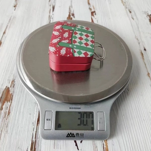 Mini Christmas tin suitcase candy box weighing 30.7g on a silver digital scale