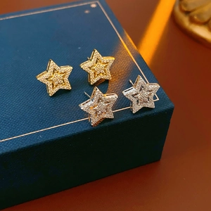 Macro shot of gold and silver star earrings with micro-inlaid zircons on a jewelry box