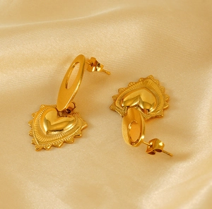 Vue détaillée des boucles d'oreilles cœur dorées avec texture radiale sur fond en soie