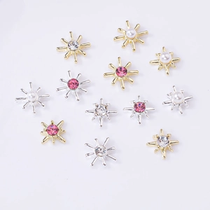 Golden and silver starburst metal nail charms with pink rhinestones and white pearls
