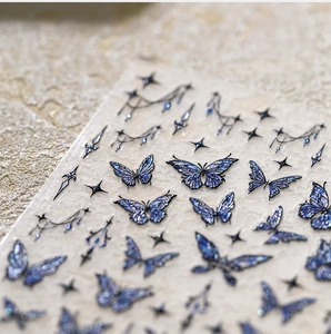 Macro detail of blue butterfly nail stickers with gold foil and sparkling glitter texture