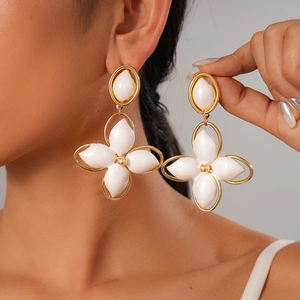 Golden oversized four-leaf clover stud earrings with white enamel fill on female model