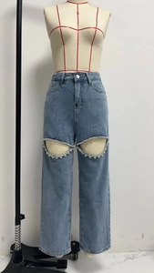 Détail de jean bleu taille haute avec découpe ornée de strass et jambe droite fluide