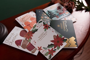 Close-up of premium gold-stamped Christmas cards featuring gingerbread and Santa designs
