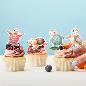 Pink and teal sea turtle cake toppers on decorated cupcakes for a birthday party setup