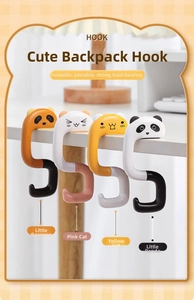 Close-up of four foldable cartoon animal desk hooks for bags on a wooden table edge