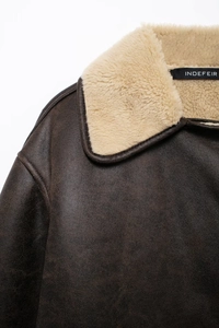 Detail of faux shearling collar and textured dark brown leather on street fashion jacket