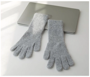Detail of grey knitted thermal gloves with plush texture next to a laptop