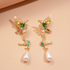Detailed macro view of vintage gold bird earrings with green heart stones and pearl drops