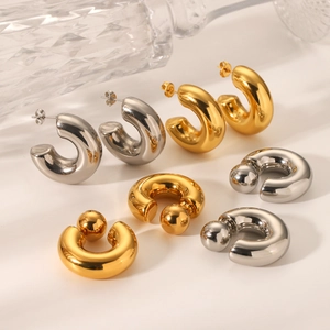 Close-up of polished C-shaped and chunky ball stud earrings in gold and silver finishes