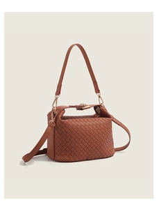 Detail of woven brown leather texture and gold buckle on a crossbody handbag