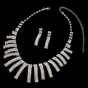Detail of silver rhinestone necklace and earring set with three rows of crystals on black background