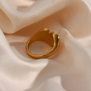Macro detail of high-polish gold heart ring on elegant white silk background