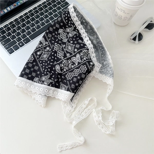 Flat lay of black paisley bandana with white lace edges and long straps for hair styling