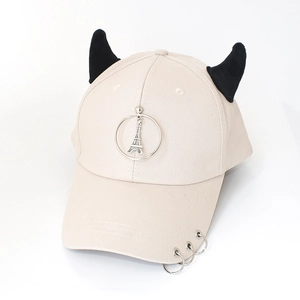 Close-up of beige baseball cap featuring black devil horns and metal ring decorations