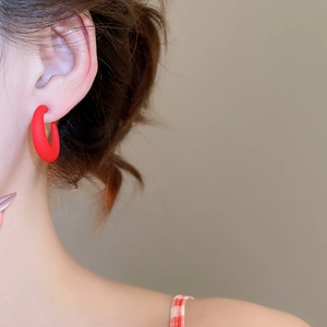 Close-up of minimalist burgundy C-shaped acrylic hoop earring with a matte finish on model