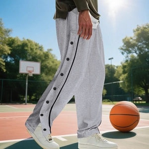 Close-up of gray basketball sweatpants featuring side snap buttons on an outdoor court