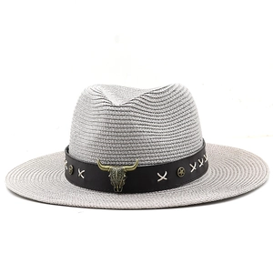Detailed macro view of woven straw fedora hat featuring a bull head badge and star rivets