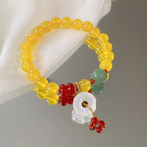 Detail eines Retro-Perlenarmbands mit weißer Blume und roter Quaste auf Spiegel