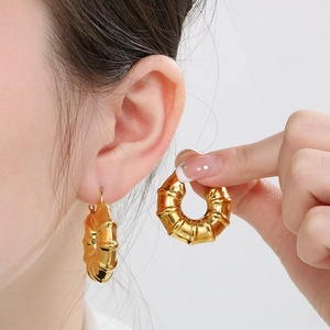 Detail of 18k gold plated stainless steel U-shaped textured hoop earring on ear