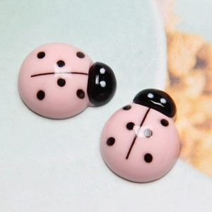 Macro detail of cute pink resin ladybug charms with black spots for DIY hair clips